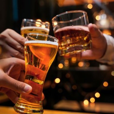 Three hands are holding different alcoholic drinks in a cheers gesture.